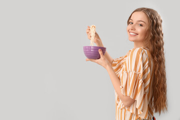 Canvas Print - Young woman with bowl of Chinese noodles on light background