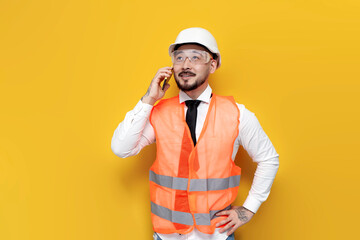 Wall Mural - asian foreman in uniform talking on the phone on yellow isolated background, korean civil engineer in hardhat