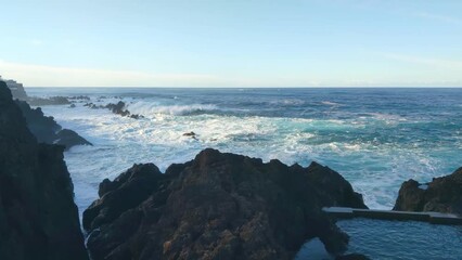 Wall Mural - Large waves of ocean or sea crash against the rocky coast. Foam and splashes from the water. The power of nature 