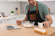 © New Africa - Man learning to cook with online video at wooden table in kitchen, closeup. Time for hobby