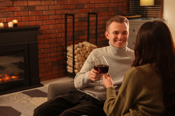 Poster - Happy lovely couple with glasses of wine resting together near fireplace at home