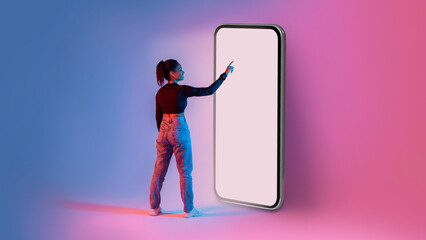 Poster - African american lady touching screen of giant smartphone in neon light, mockup for mobile app or website design