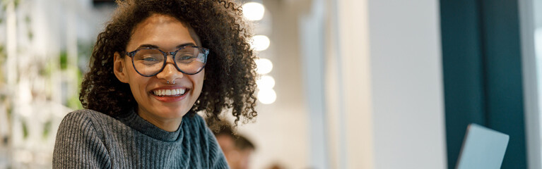 Smiling afro american woman student studying online while sitting in cozy cafe