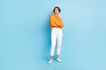 Full size photo of pretty young girl folded hands look empty space freelancer wear trendy orange garment isolated on blue color background