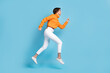 © deagreez - Full size photo of pretty young girl profile view running hurry speed fast dressed stylish orange look isolated on blue color background