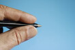 El hombre con la mano izquierda sostiene el bolígrafo con los dedos en la oficina para escribir las notas diarias de su trabajo, diseño original con fondo azul-celeste