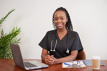 Portrait of Black female doctor sitting at office desk ready for consult