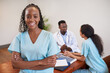 © Meeko Media - Portrait of smiling nurse standing in medical conference room with colleagues