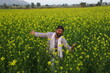 © Maahir - Happy Indian farmer enjoying the wind standing in the field spreading his arms and looking up in the sky.