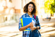 © Minerva Studio - Female african student holding a book in a college park