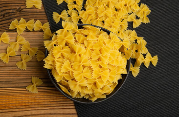 Wall Mural - Raw Farfalle Pasta on Wooden Table, Yellow Dry Noodles, Wheat Bow Macaroni, Uncooked Farfalle Top View