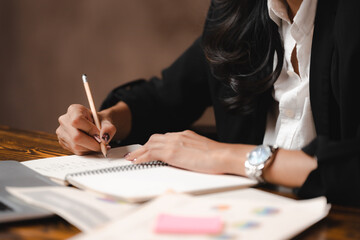 asian businesswoman reviewing document reports and signing contract at office workplace with compute