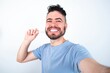 © Jihan - Young caucasian man wearing blue T-shirt over white background make selfie holding an invisible braces aligner, recommending this new treatment. Dental healthcare concept.