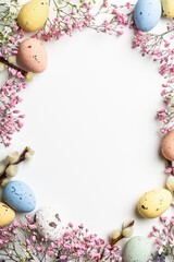 Wall Mural - Shot from above of Easter composition with spring flowers and colorful quail eggs over white background. Springtime and Easter holiday concept with copy space. Top view