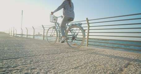 Wall Mural - Carefree woman with bike riding on sand beach having fun, on the seaside promenade on a summer day.
