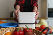Woman holding compost bin. Female cooking dinner at home and recycling organic waste in a bokashi container. Person using ferment to decompose food leftovers into fertilizer
