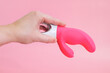 © Galina - Vibrator in female hand, sex toys concept. Waterproof adult sex toy from body-safe silicone on pink background. G-spot vibrator with clitoral stimulator from medical grade silicone.