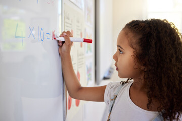 Whiteboard, math and girl writing for learning, studying and education in classroom. Development, mathematics and kid or student write equations, numbers and multiplication in elementary school.