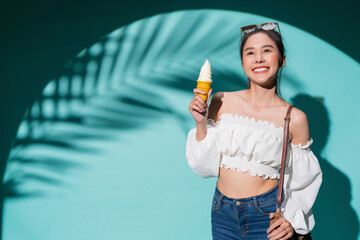 enjoy smiling attractive asia teen female woman wear casual t-shirt cloth happiness facial expression hand hold ice cream waffle cone summer lifestyle vacation travel studio shot on blue colour 