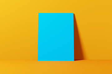 Empty blank blue poster leaning on a yellow wall.