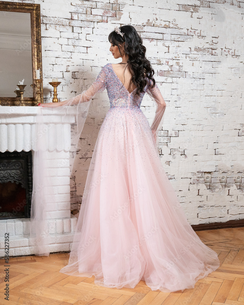 Woman in a pink dress standing in front of a brick wall Stock Photo ...