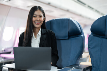 Female passenger sitting on plane while working on laptop computer with simulated space using on board wireless connection