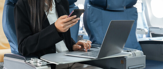 transport, tourism and technology concept - close up of business woman with smartphone and laptop traveling by plane