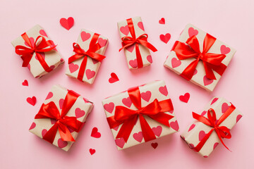 Top view photo of valentine day decorations gift box with red ribbon bow on colored background. Holiday gift boxes with top view