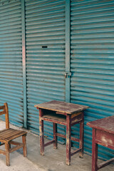 Wall Mural - Abandoned wooden desk and chair in front of blue shutter door in Taiwan