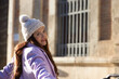 © @skuder_photographer - beautiful young spanish woman with woollen cap is leaning on the chains surrounding the cathedral of seville in spain. The woman is happy and enjoying her holiday in the city.