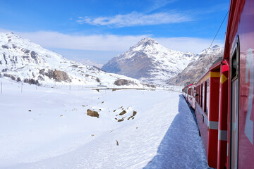 Bernina mountain pass. The famous red train is crossing the white lake. Amazing landscape of the Switzerland land. Famous destination and tourists attraction