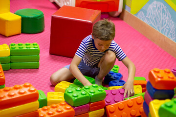 Cute boy playing with building toy colorful blocks. Preschool activities and early childhood education. Kid with happy face playing with plastic bricks. Plastic Large Toy. big cubes bricks