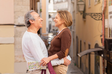 Wall Mural - Senior Spouses Hugging Standing On Street In European City Outside