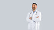 © Prostock-studio - Medical worker. Happy male doctor in uniform posing with folded arms over grey studio background, panorama, free space