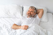 High angle view of positive mature man lying in bed