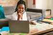 Happy black woman planning vacation with map and laptop, choosing best travel routes for future journey