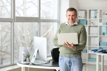 Wall Mural - Mature accountant working with laptop in office