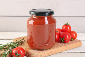 Board with jar of tasty tomato paste on white wooden background