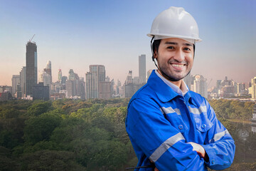 Wall Mural - Portrait of manual Indian man worker is standing with confident with working suite dress and safety helmet in front ิีbuilding cityscape. Green city with hi rise modern architecture and clear sky.