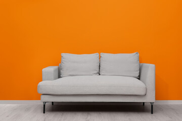 Wall Mural - Comfortable sofa near bright orange wall indoors