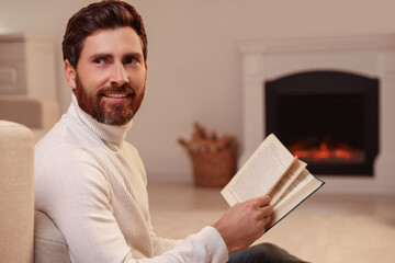 Sticker - Handsome man reading book near fireplace in room