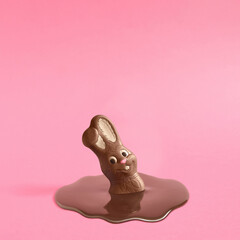 Trendy composition with Easter chocolate bunny rabbit melting on pink pastel background .Creative art, minimal aesthetic look. Contemporary style.Writing space, copy space, minimal easter concept