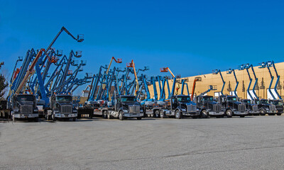 Construction machinery for rent. Lifts with raised platforms and cargo trucks are at the industrial court yard