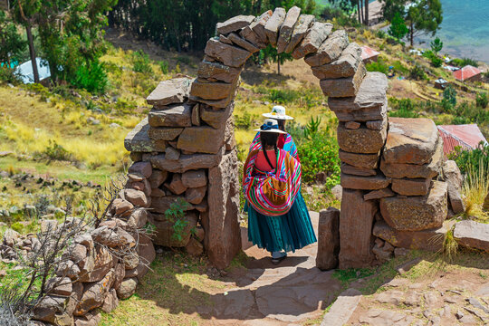 peruvian indigenous quechua women in traditional clothing walking on isla taquile, titicaca lake, pe