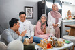 © Odua Images - Muslim friends laughing together while celebrating Idul Fitri at home