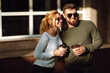 © maxbelchenko - Young couple having fun talking, drinking coffee and using the phone while walking in the morning city. Relaxation, youth, love, lifestyle, selfie, blogging.