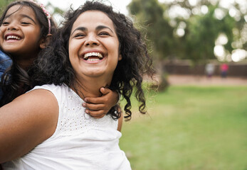 Wall Mural - happy indian mother having fun with her daughter outdoor - family, mom day and love concept - focus 