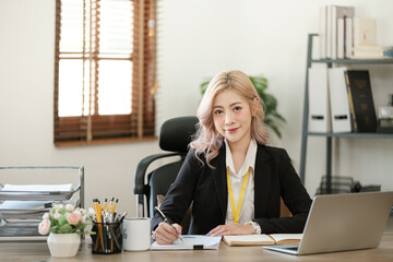 Close up on laptop in office, Asian happy beautiful businesswoman in formal suit work in workplace. Attractive female employee office worker smile.