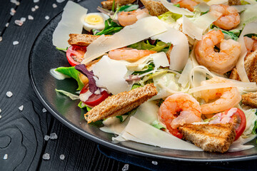 Wall Mural - Caesar salad with grilled shrimp on a dark background, top view