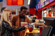 © bernardbodo - Multiethnic couple at cash register in movie theater.